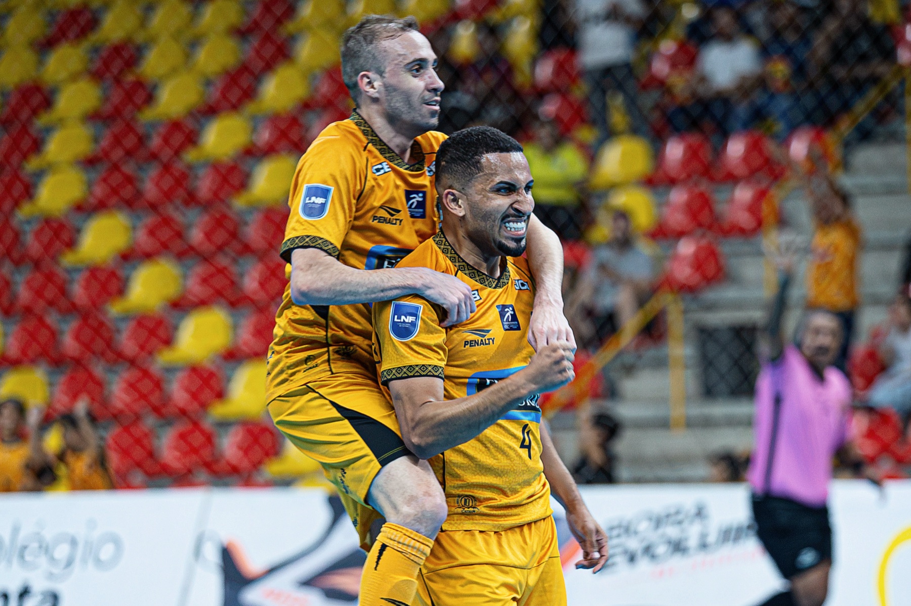 Jogadores do Magnus Futsal comemorando gol abracados na quadra